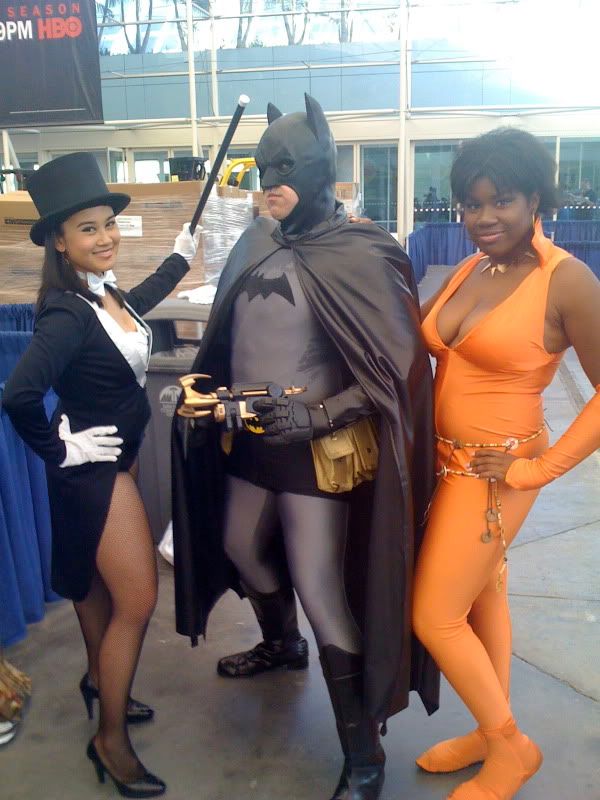 Compensating for something?  Oh the phallic fun!  Batman pokes his gun at a lucky lady while another feminine superhero stands in the wings.